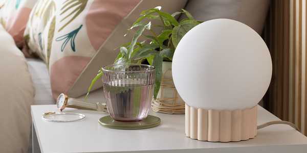 A large round table lamp on a bedside table.